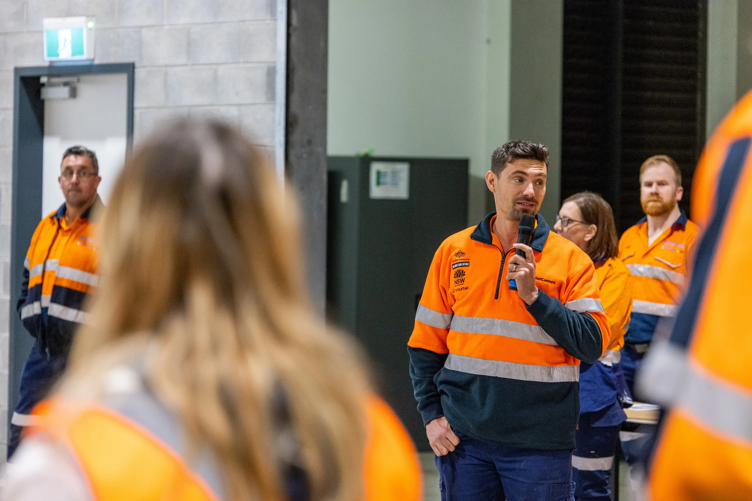 Jeremiah Hartmann speaking with a microphone during a WestConnex toolbox talk